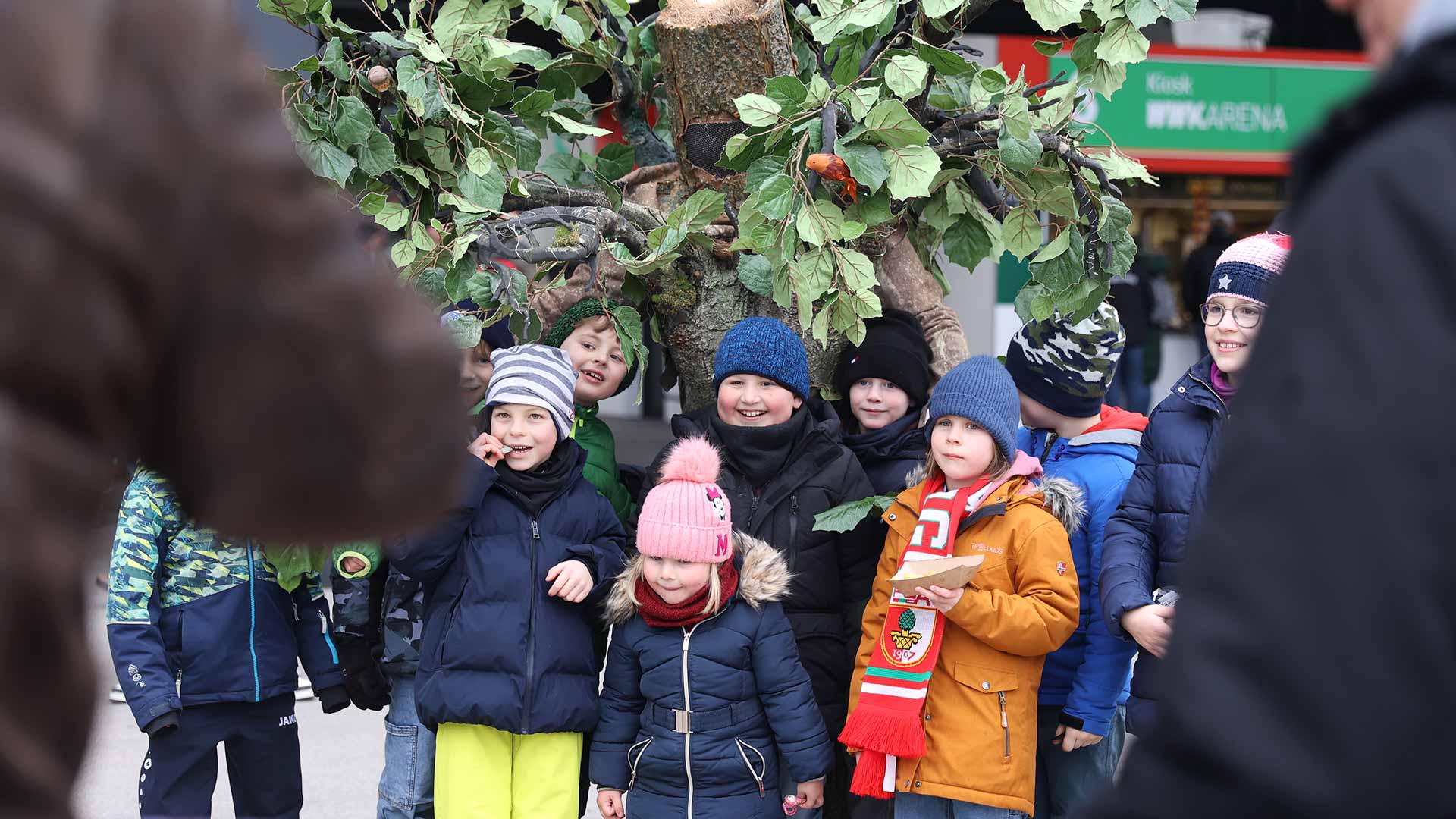Kinder lassen sich gemeinsam mit einem als Baum verkleideten Menschen fotografieren.